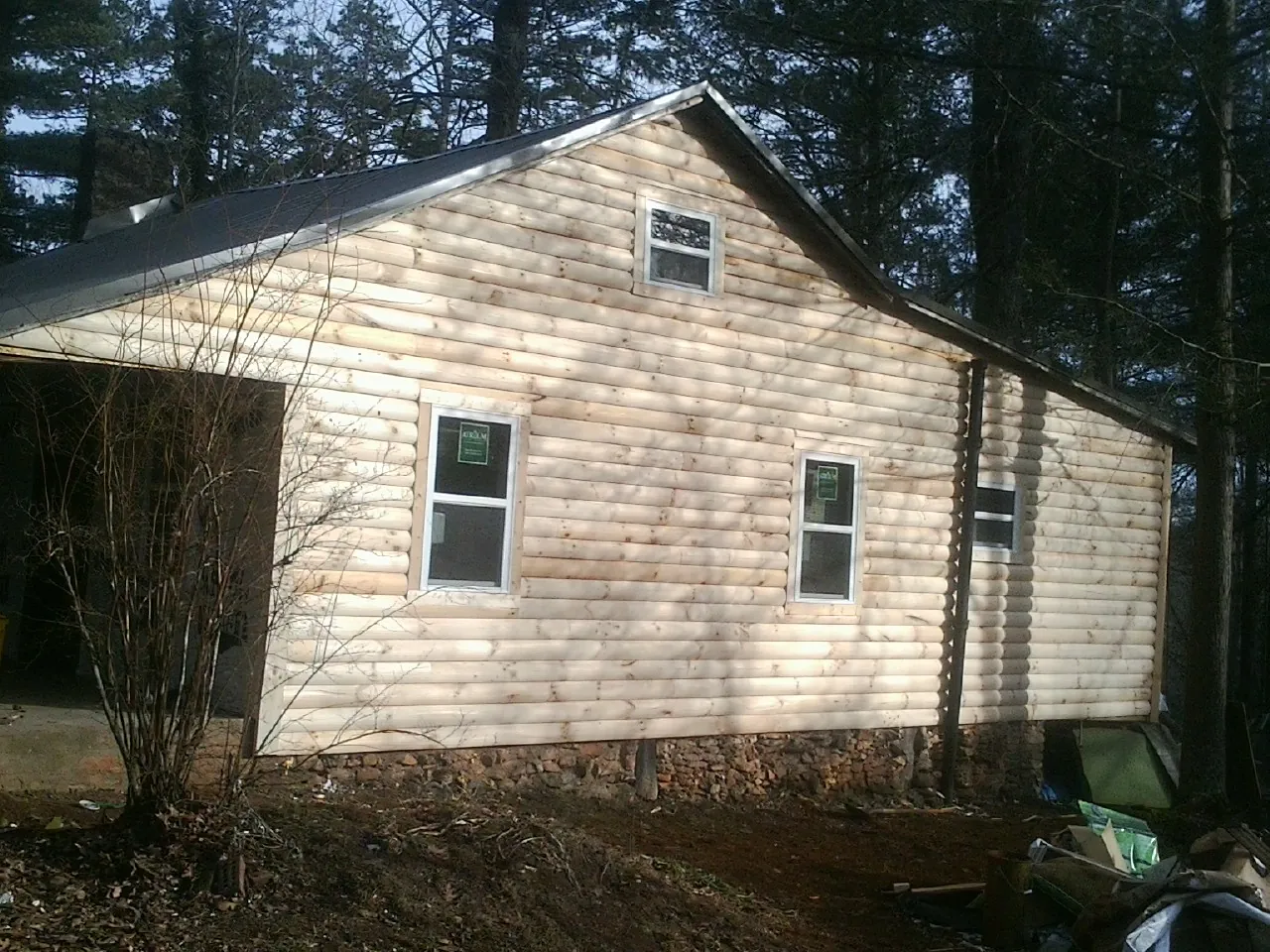 New log siding and dark metal roofing on a gable end in Forest City