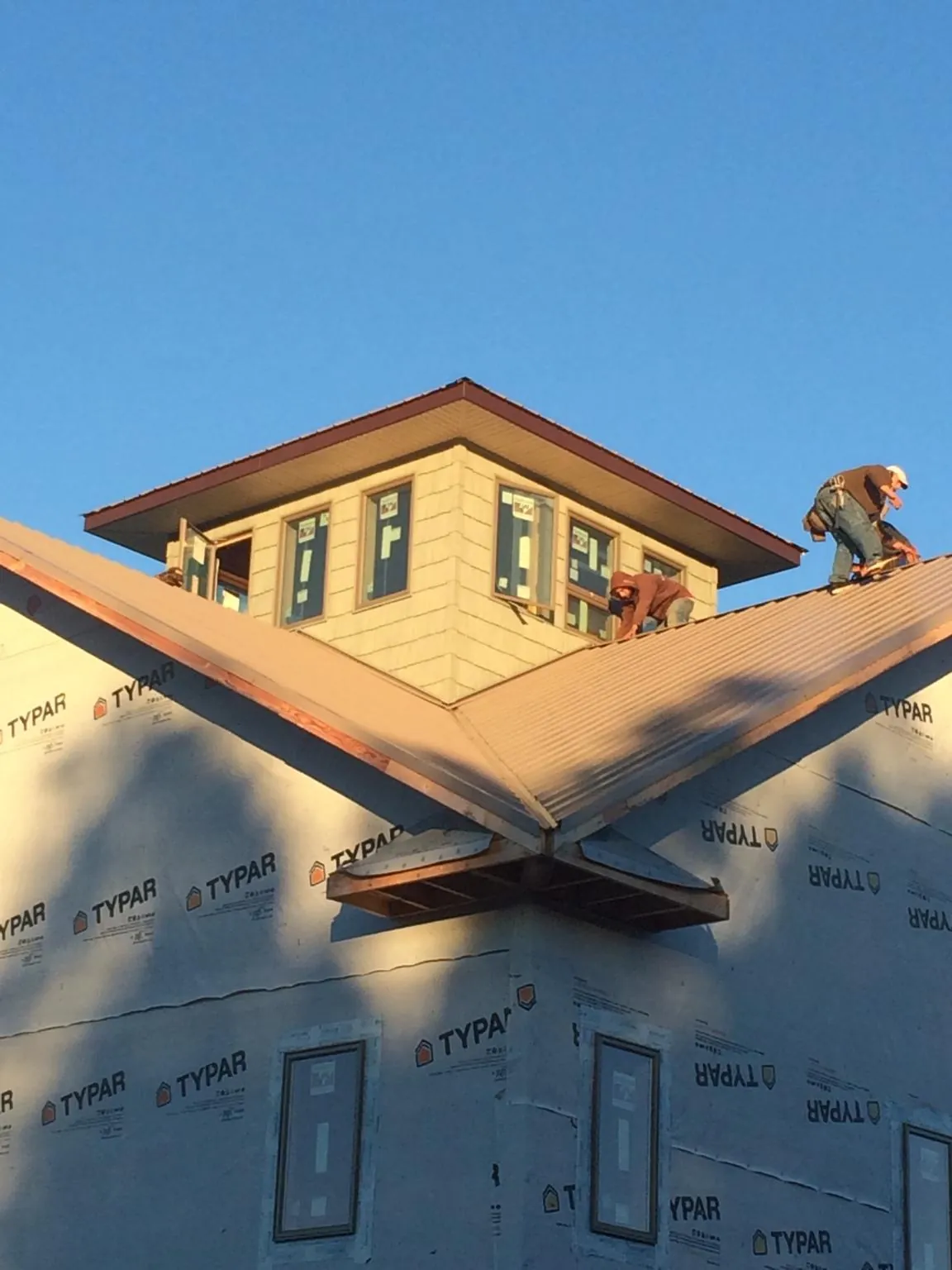 Roofers working around a rooftop cupola on a new metal roof at sunset — Roof Waterproofing in Forest City by Roofing Brothers